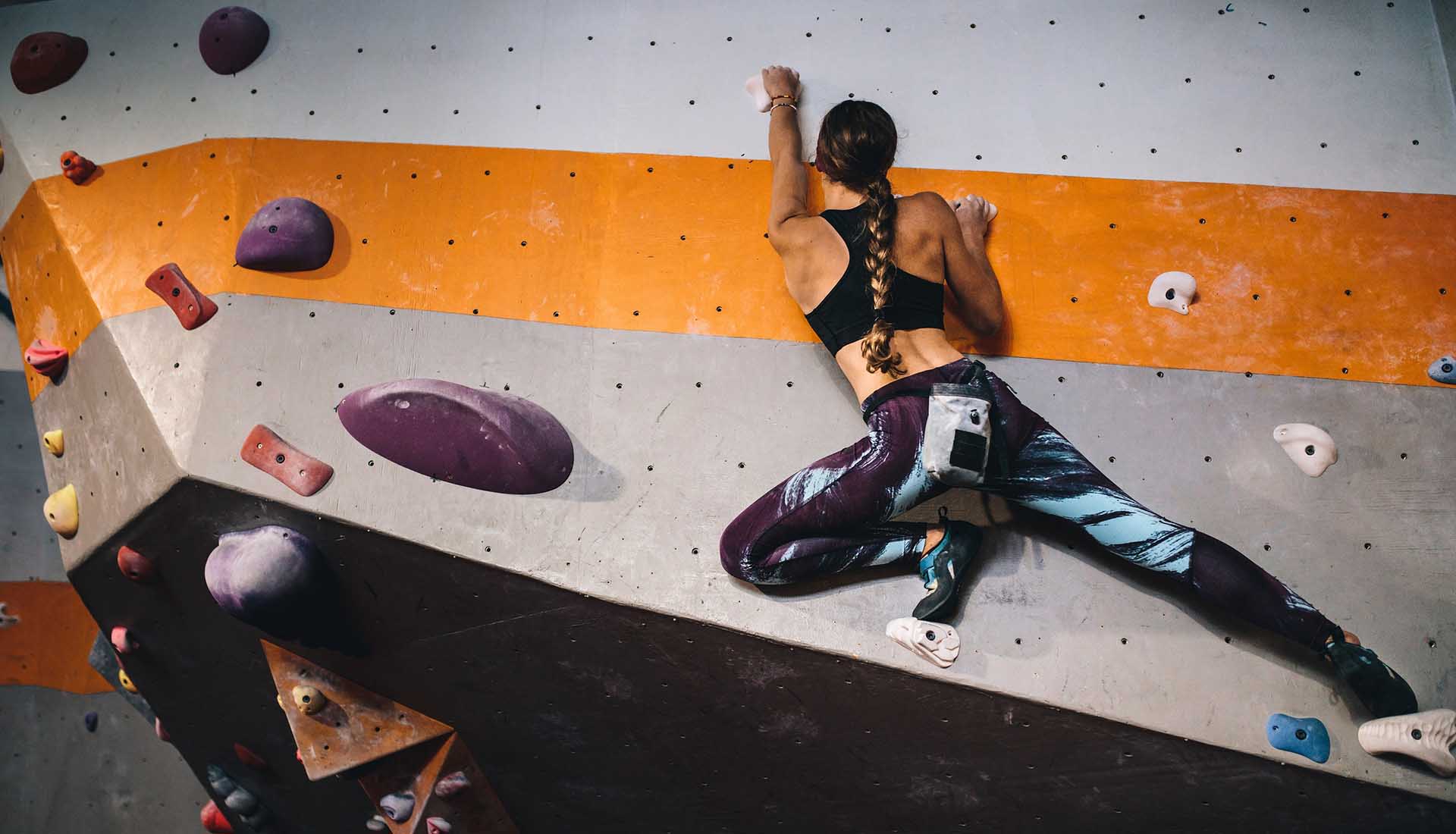 Woman learning the art of rock climbing at an indoor climbing center.