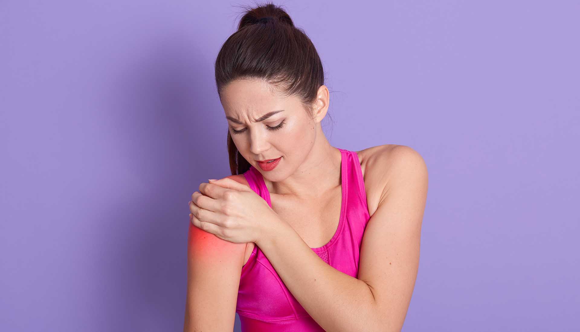 Portrait of sporty woman putting her hand on injury shoulder.