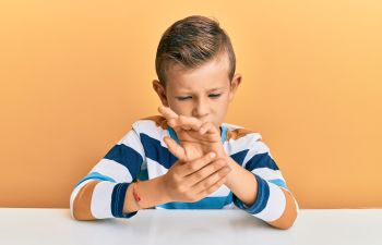 A boy touching his stiff painful wrist joint.